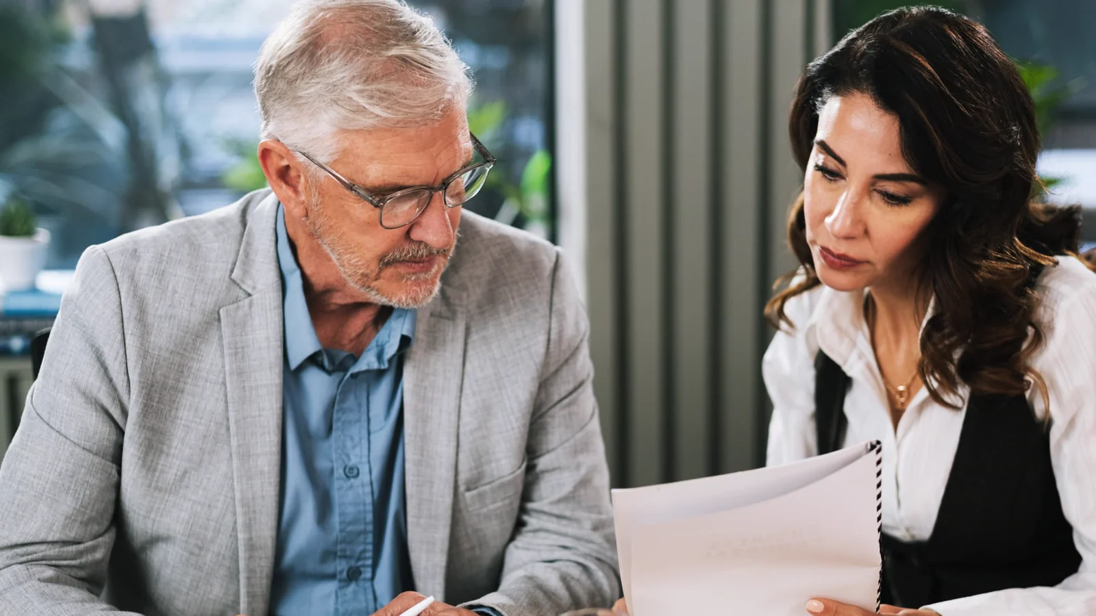Two senior professionals reviewing workplace documents