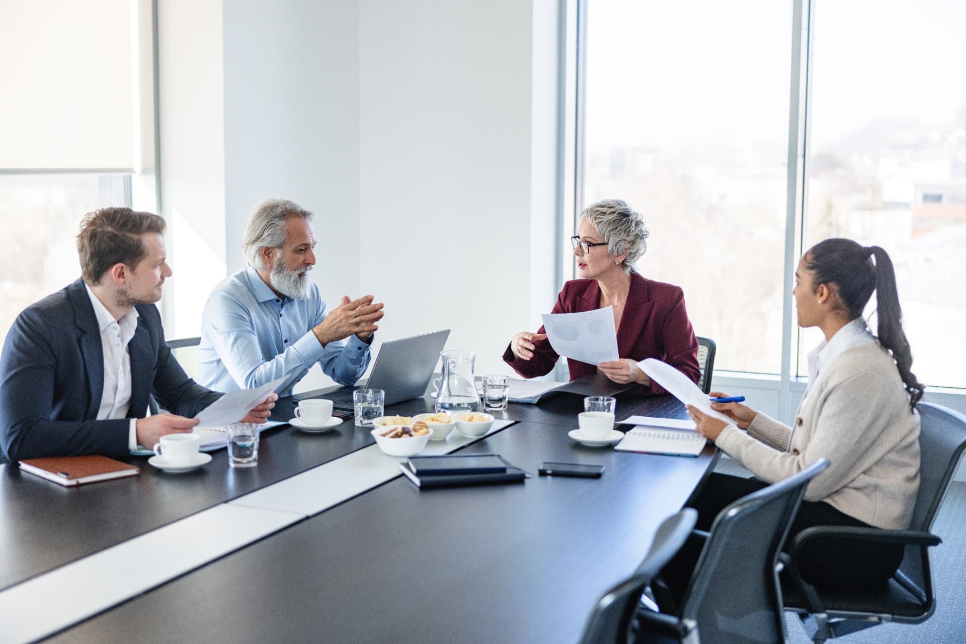 Four colleagues discussing printed reports around a meeting table