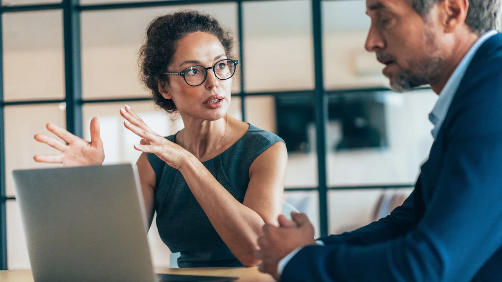 Two business colleagues discussing a flexible work arrangement beside an open laptop