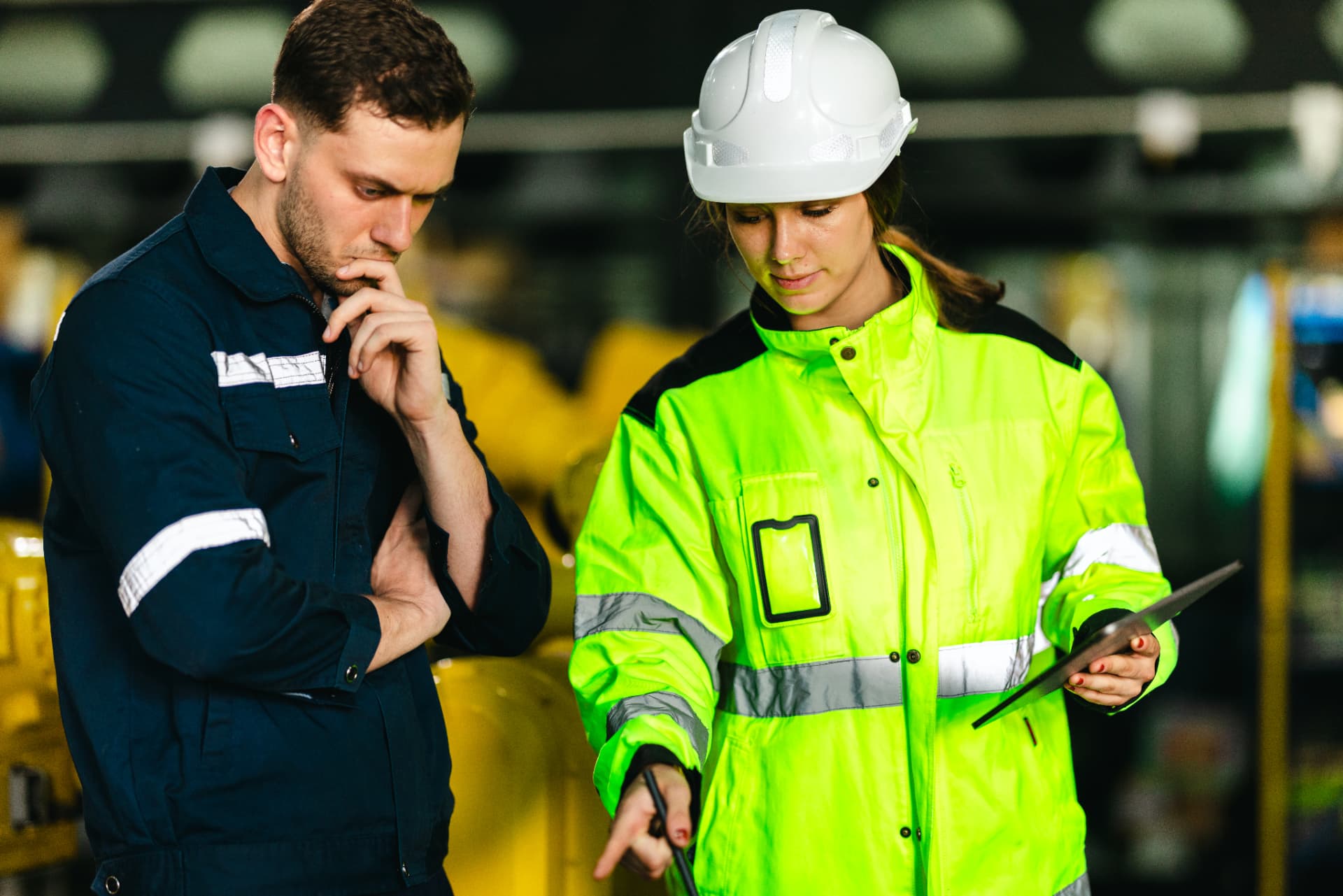 Two workers reviewing a tablet at an industrial workplace