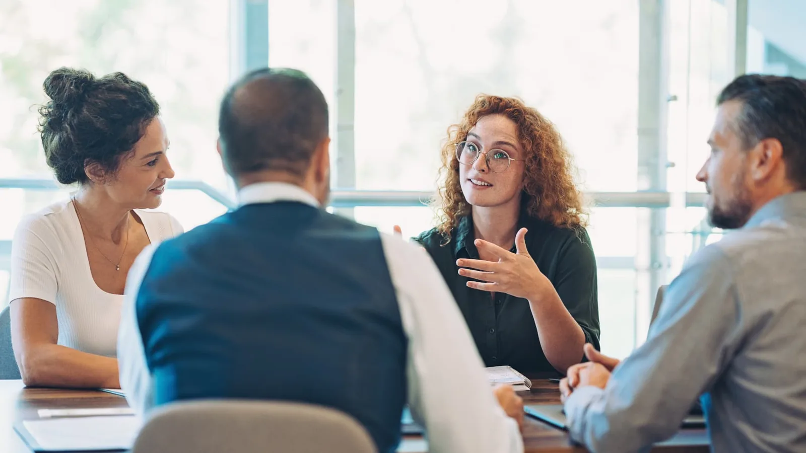 One employee speaking with three coworkers during a workplace meeting