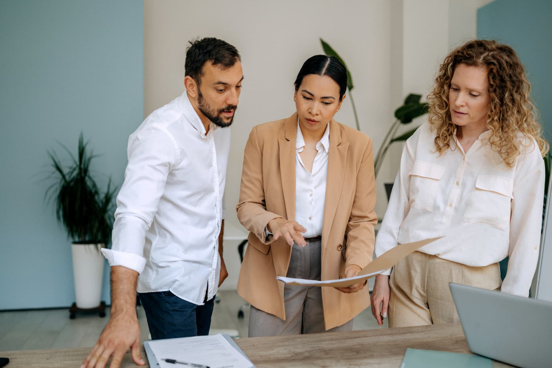 Three colleagues reviewing printed documents together at a table